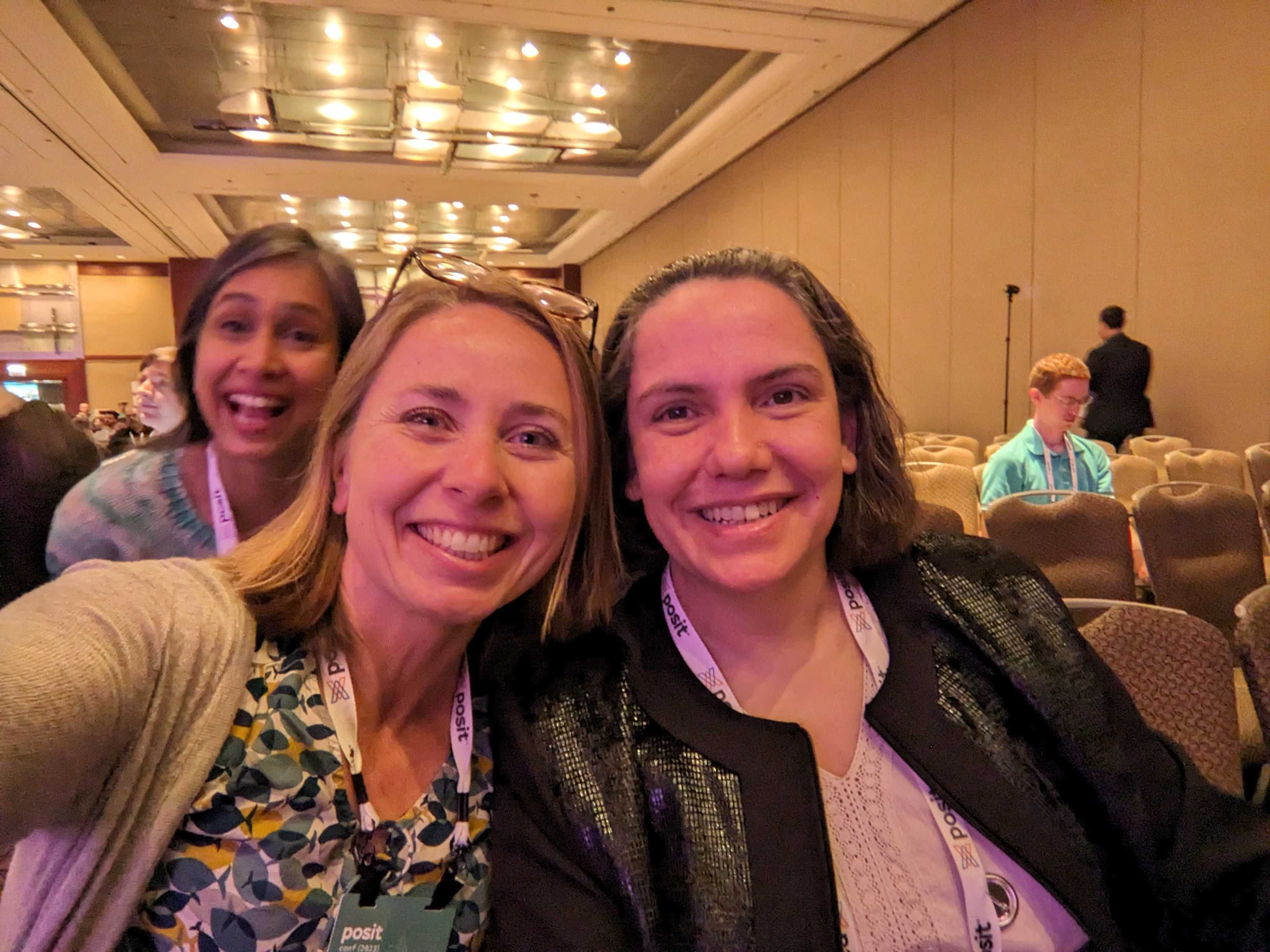 smiling selfie photo of Julie Lowndes & Yanina Bellini Saibene in foreground with a smiling Deepsha Menghani, photobombing in near background, 
