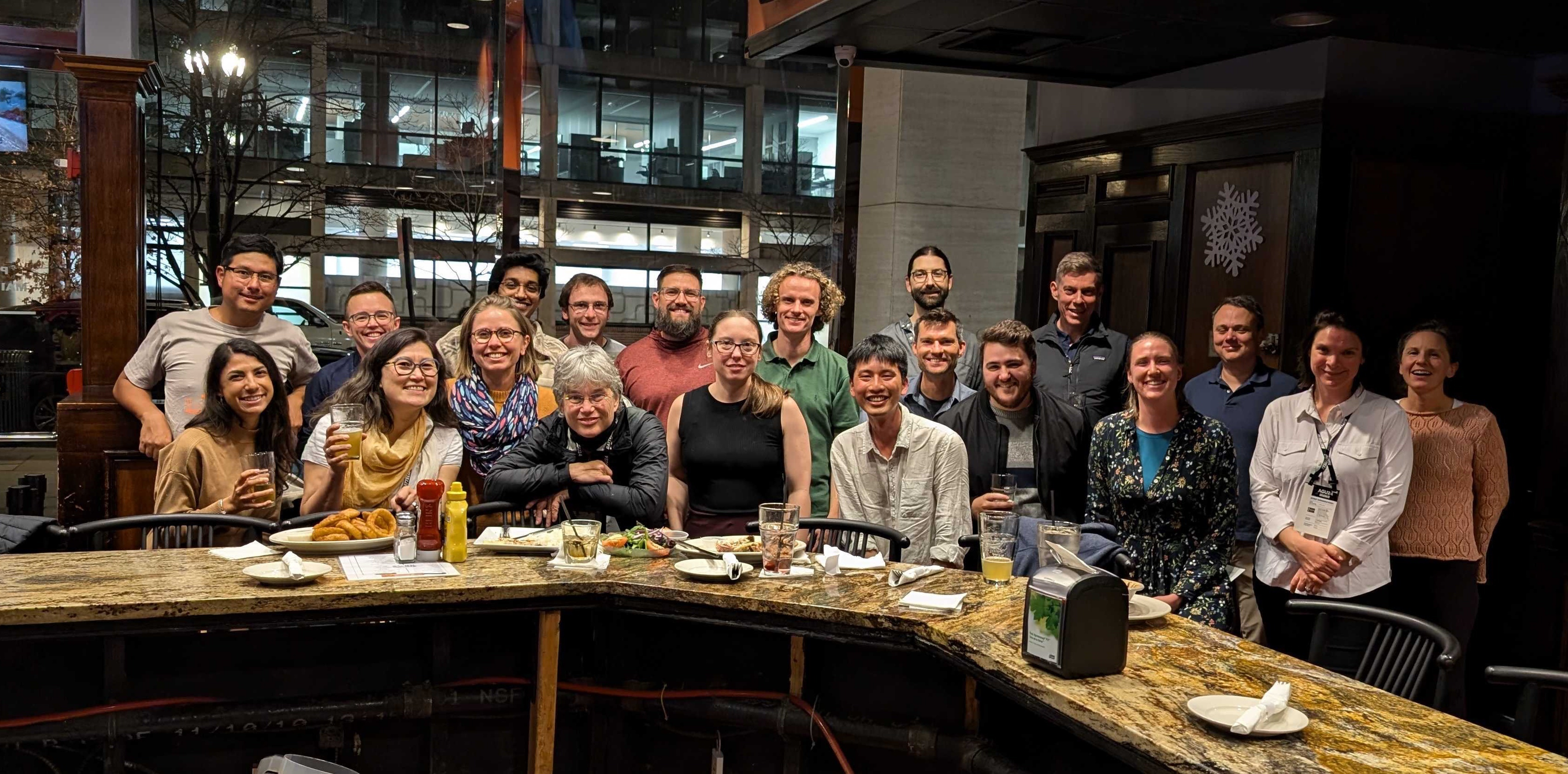 photo of 20 smiling women and men inside a restaurant